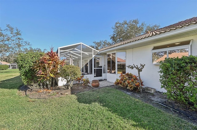 back of property with glass enclosure and a yard