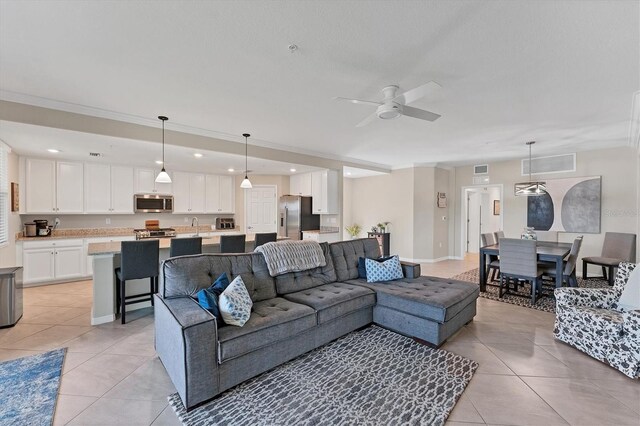 tiled living room featuring ceiling fan, sink, and crown molding