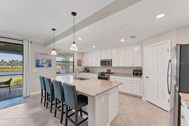 kitchen with a kitchen island with sink, sink, light stone countertops, decorative light fixtures, and stainless steel appliances