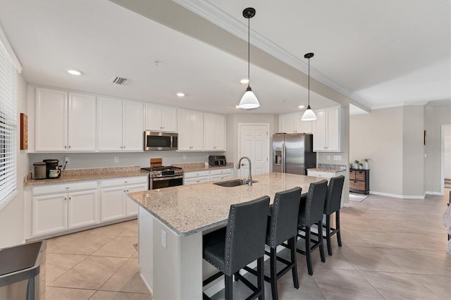 kitchen with light stone counters, stainless steel appliances, sink, a center island with sink, and white cabinetry