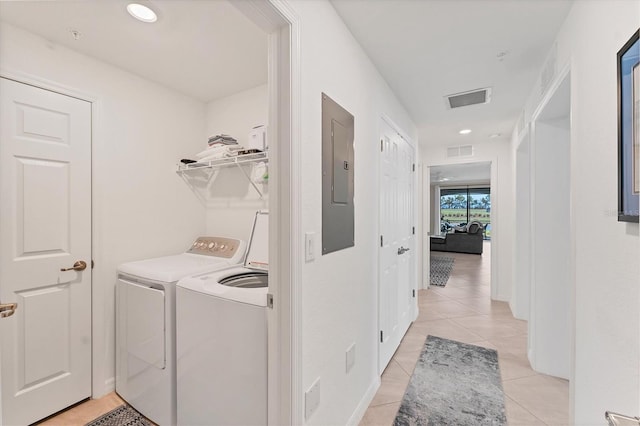 clothes washing area with independent washer and dryer, light tile patterned floors, and electric panel