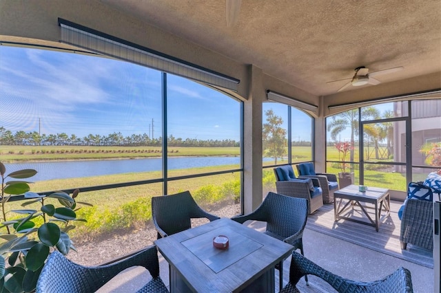 sunroom featuring ceiling fan and a water view