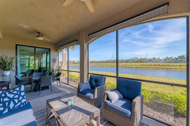 sunroom with ceiling fan and a water view