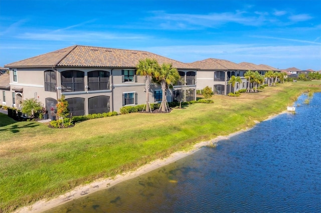 back of property featuring a water view and a lawn