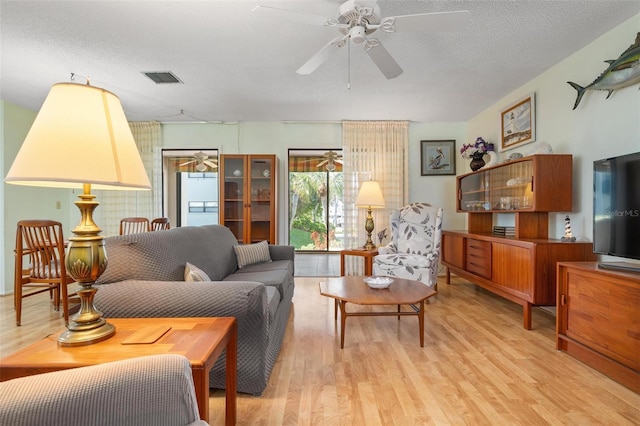 living room with ceiling fan, light hardwood / wood-style floors, and a textured ceiling