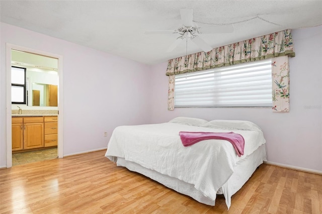 bedroom featuring ensuite bath, ceiling fan, sink, and light wood-type flooring