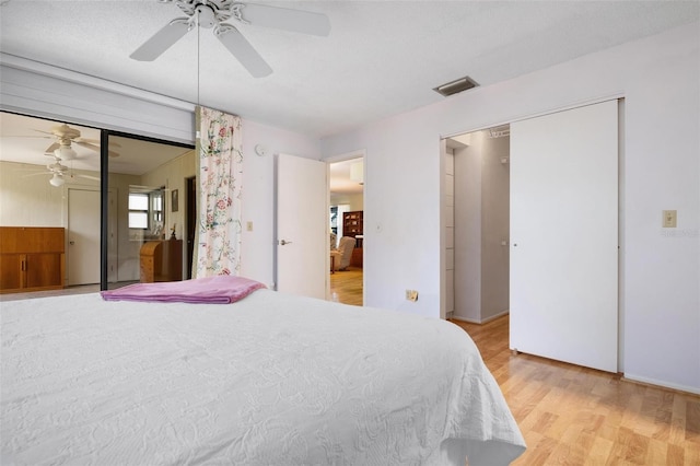 bedroom with ceiling fan, light hardwood / wood-style floors, and a closet