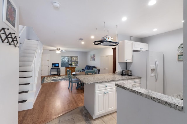 kitchen featuring ceiling fan, light hardwood / wood-style flooring, white cabinets, and white refrigerator with ice dispenser