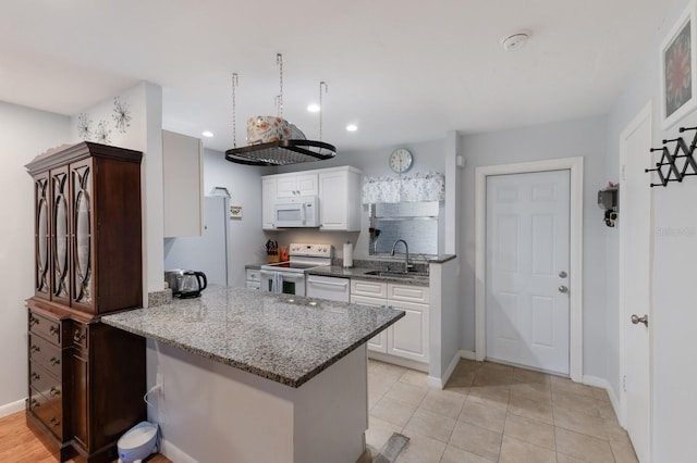 kitchen featuring white appliances, stone counters, sink, kitchen peninsula, and white cabinetry