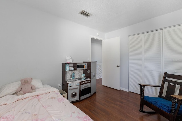 bedroom featuring a closet, dark wood-type flooring, and a textured ceiling