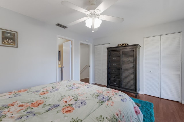 bedroom with ceiling fan, dark hardwood / wood-style flooring, and two closets