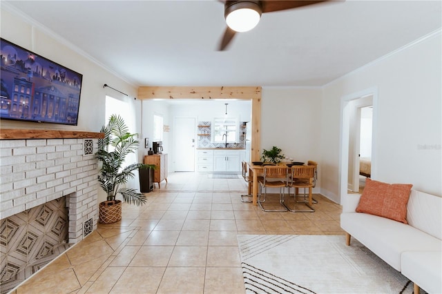 tiled living room featuring a fireplace, ceiling fan, crown molding, and sink