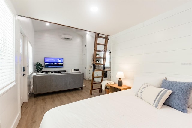 bedroom with multiple windows, light hardwood / wood-style flooring, and a wall mounted air conditioner