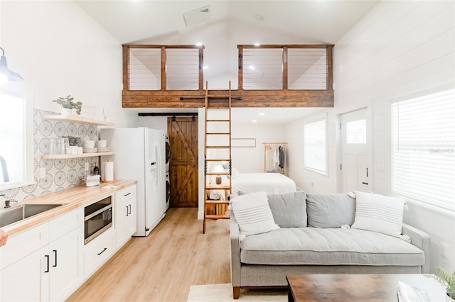 kitchen featuring wooden counters, white cabinets, a barn door, white fridge with ice dispenser, and light hardwood / wood-style floors