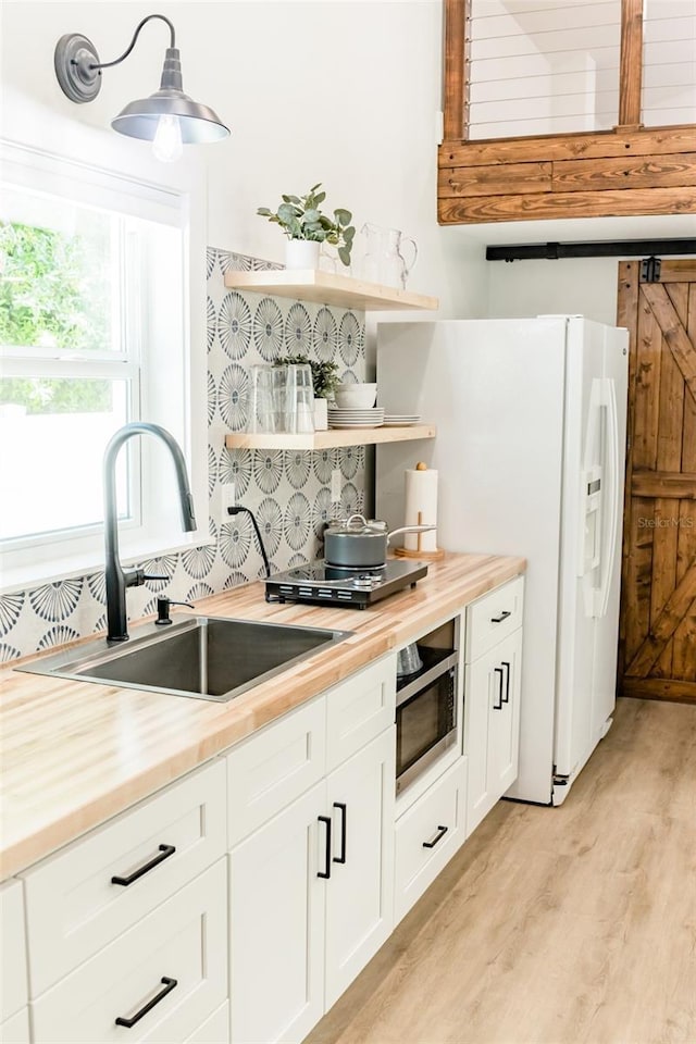 kitchen with white cabinets, decorative light fixtures, butcher block counters, and sink