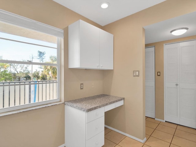 kitchen featuring built in desk, white cabinetry, and light tile patterned floors