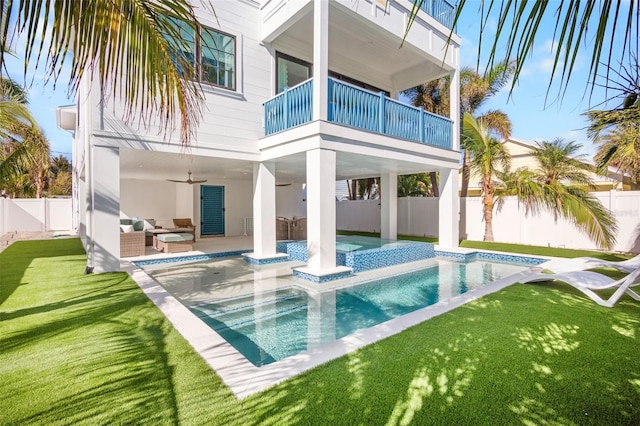 back of house with outdoor lounge area, a fenced in pool, ceiling fan, a balcony, and a yard