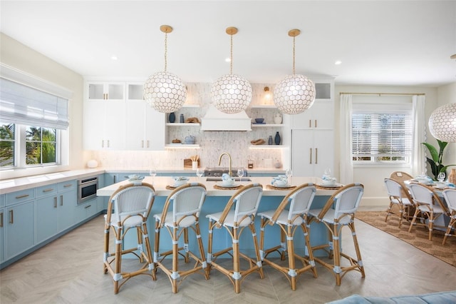 kitchen featuring white cabinetry, sink, decorative light fixtures, decorative backsplash, and a kitchen island