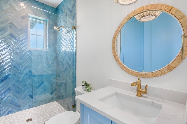 bathroom with tiled shower, vanity, and toilet