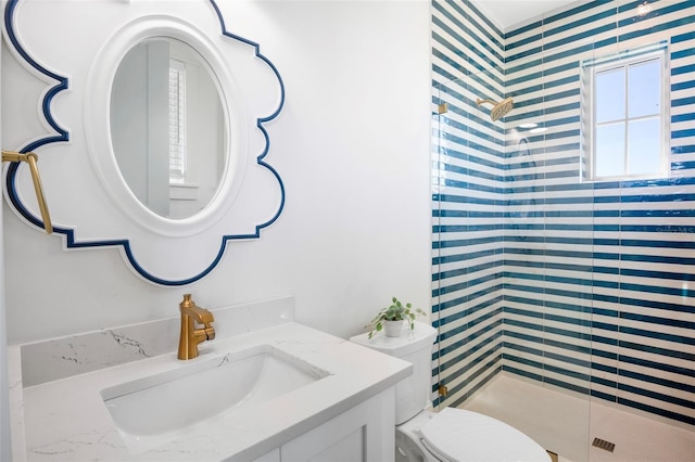 bathroom with a shower with door, vanity, and toilet