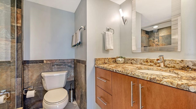 bathroom featuring vanity, tile walls, and toilet