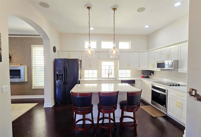 kitchen with dark wood-type flooring, sink, black appliances, white cabinets, and a kitchen island