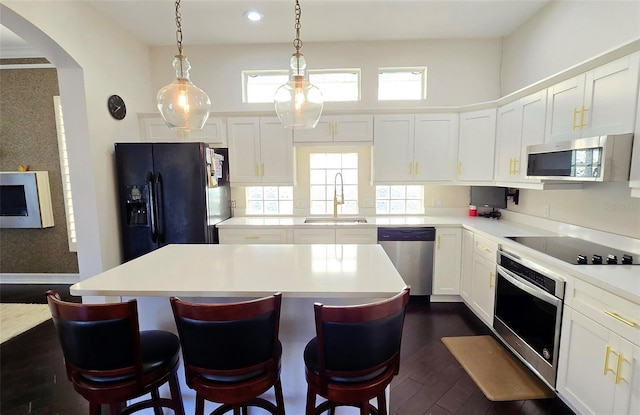 kitchen with black appliances, a center island, white cabinets, and dark wood-type flooring