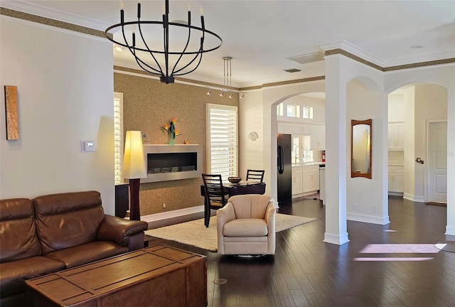 living room featuring sink, an inviting chandelier, dark wood-type flooring, and crown molding