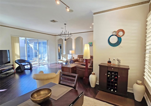 living room featuring dark hardwood / wood-style flooring, a chandelier, and ornamental molding