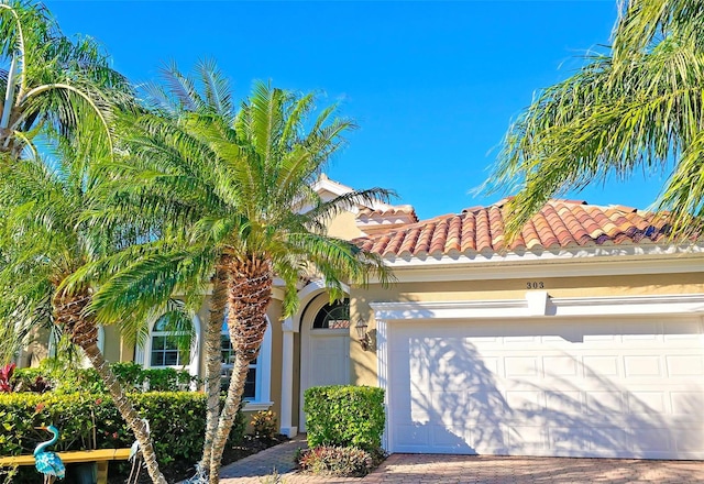 view of front of home featuring a garage, decorative driveway, a tile roof, and stucco siding