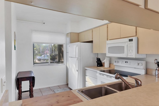 kitchen with cream cabinets, light tile patterned flooring, white appliances, and sink