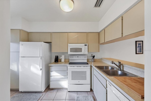 kitchen with cream cabinets, light tile patterned flooring, white appliances, and sink