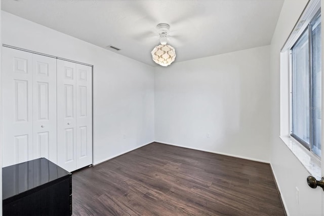 2124 N Tamiami Trl Unit 103, Sarasota, FL 34234 - unfurnished bedroom with multiple windows, dark wood-type flooring, baseboards, and a closet