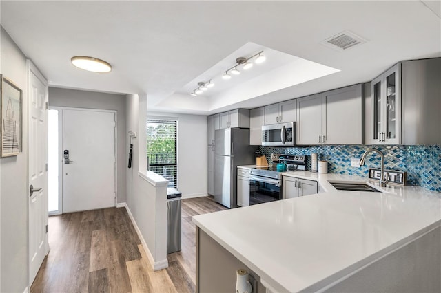 kitchen with light hardwood / wood-style floors, kitchen peninsula, sink, and appliances with stainless steel finishes