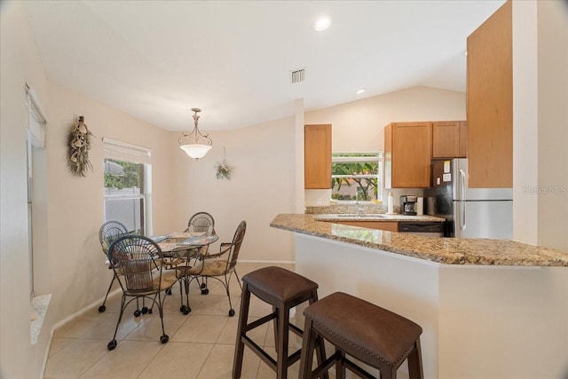 kitchen with light stone countertops, appliances with stainless steel finishes, kitchen peninsula, and lofted ceiling