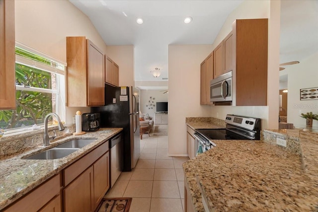 kitchen with appliances with stainless steel finishes, light stone counters, ceiling fan, sink, and light tile patterned floors