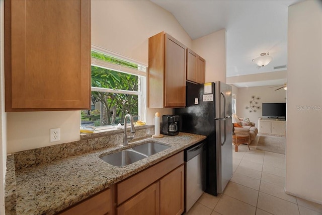 kitchen with light stone countertops, stainless steel appliances, ceiling fan, sink, and lofted ceiling