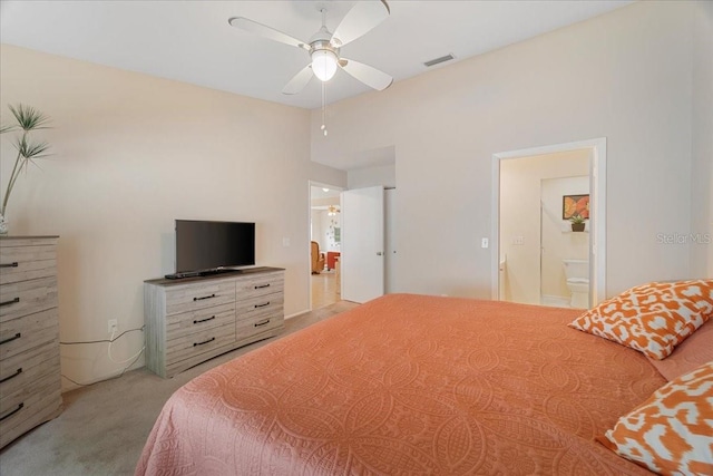 bedroom with ensuite bath, ceiling fan, and light colored carpet