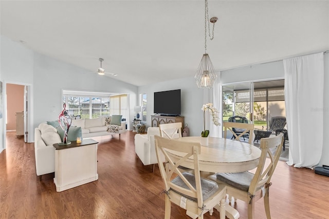 dining space with ceiling fan with notable chandelier, lofted ceiling, and hardwood / wood-style flooring