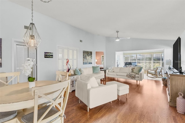 living room featuring ceiling fan with notable chandelier, wood-type flooring, and high vaulted ceiling