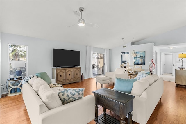 living room with light hardwood / wood-style flooring, vaulted ceiling, and ceiling fan