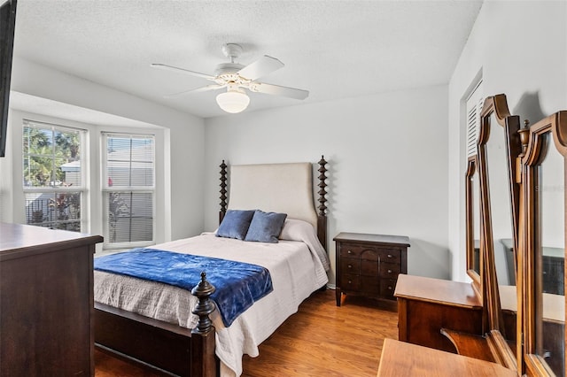 bedroom with a textured ceiling, light hardwood / wood-style flooring, and ceiling fan