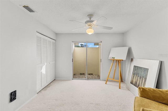 living area with carpet, ceiling fan, and a textured ceiling