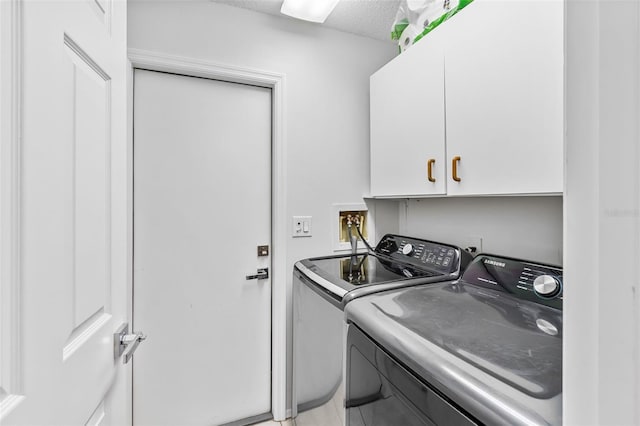 laundry room featuring cabinets, a textured ceiling, and washer and clothes dryer