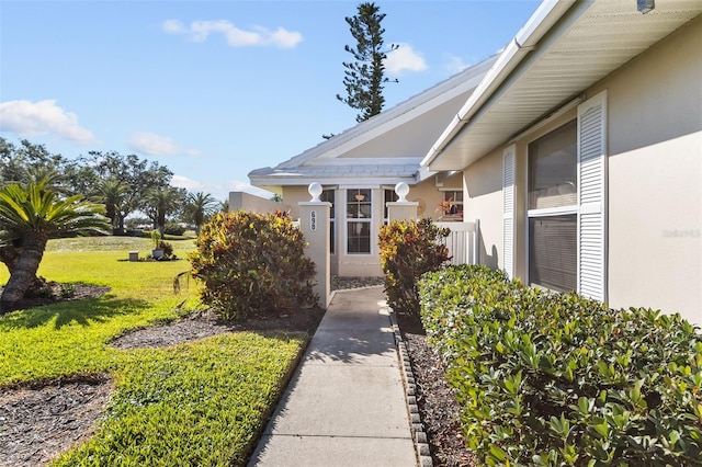 view of exterior entry featuring a lawn