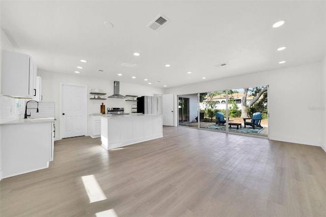 unfurnished living room featuring sink and light hardwood / wood-style flooring