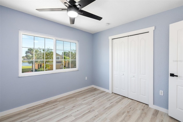 unfurnished bedroom with ceiling fan, a closet, and light wood-type flooring