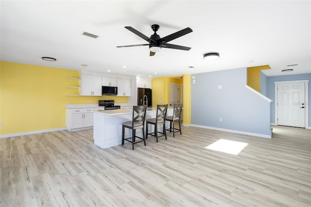 kitchen featuring range with electric cooktop, white cabinets, a kitchen breakfast bar, a kitchen island with sink, and black refrigerator with ice dispenser