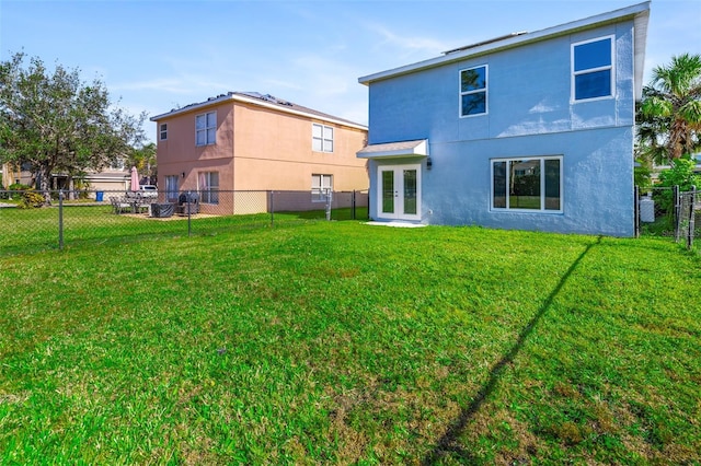 back of house with french doors and a lawn