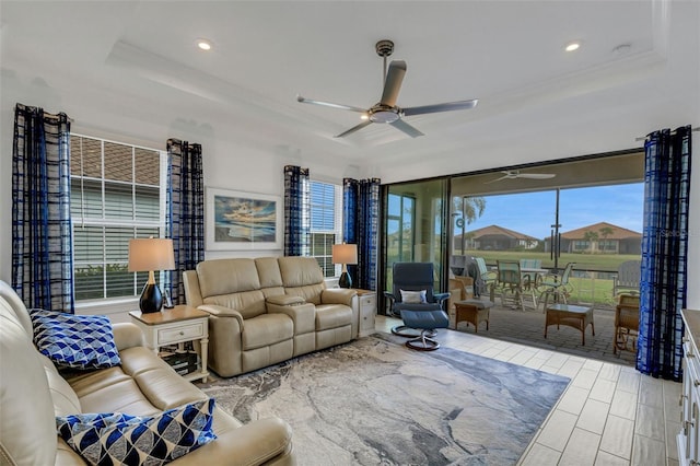 living room with ceiling fan, a raised ceiling, and a wealth of natural light